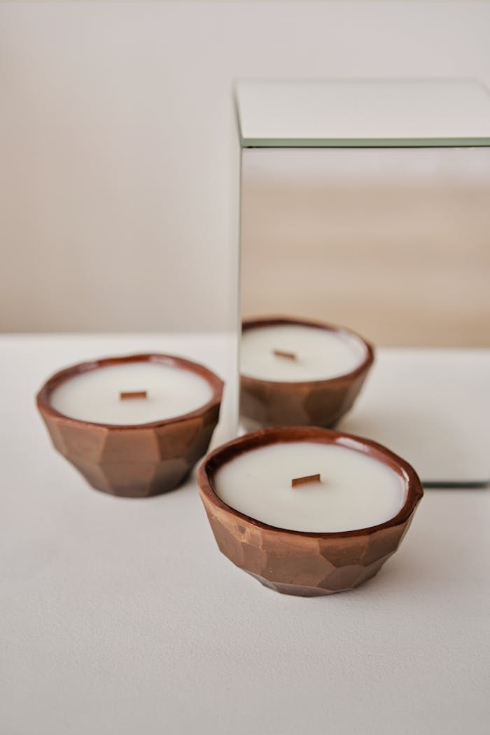 Wax candles in geometric holders near mirror